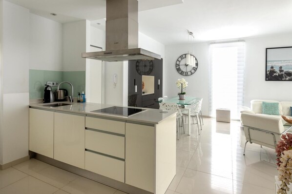 Una cocina moderna con una isla central, estufa integrada y un reloj grande en la pared.