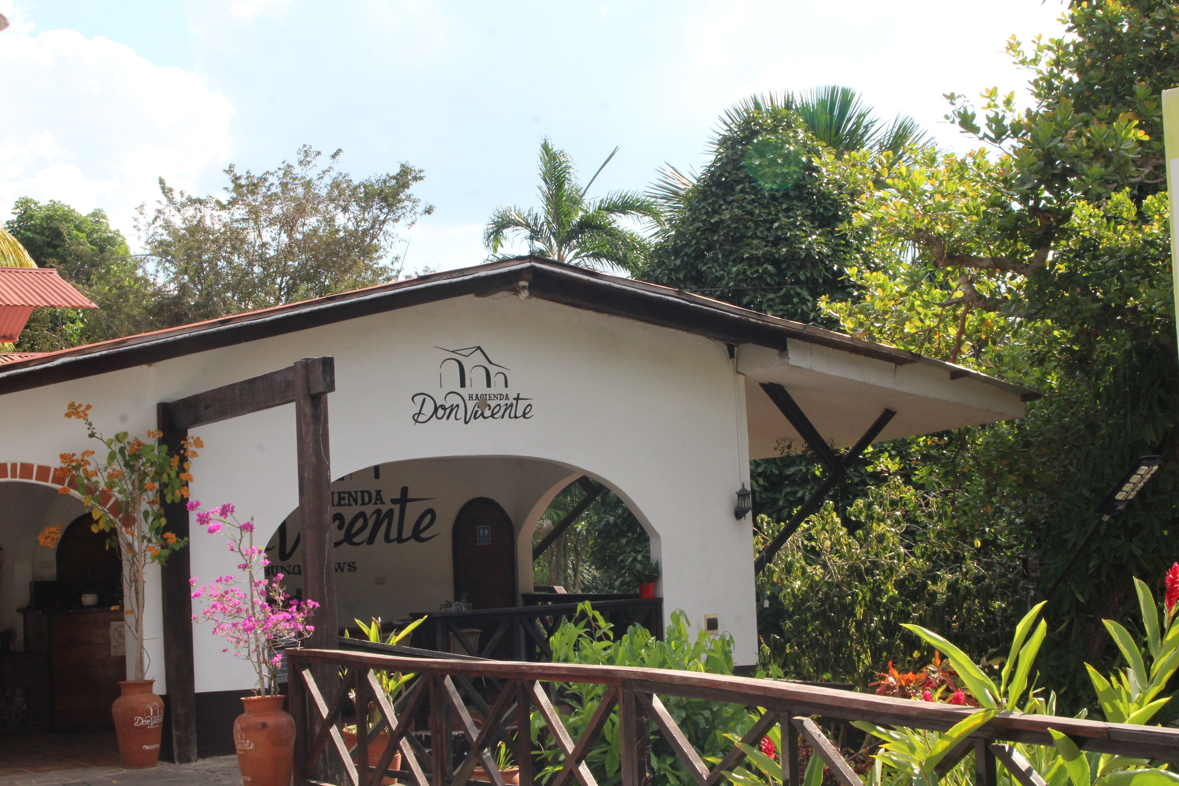 A building with a sign reading "Don Vicente." It features a white facade with wooden beams, arched doorways, and a small porch area.