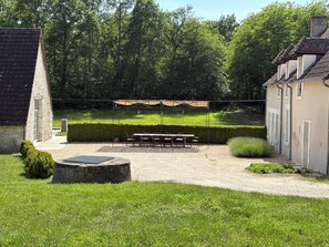 A courtyard with a picnic table, a covered seating area, and a stone well.