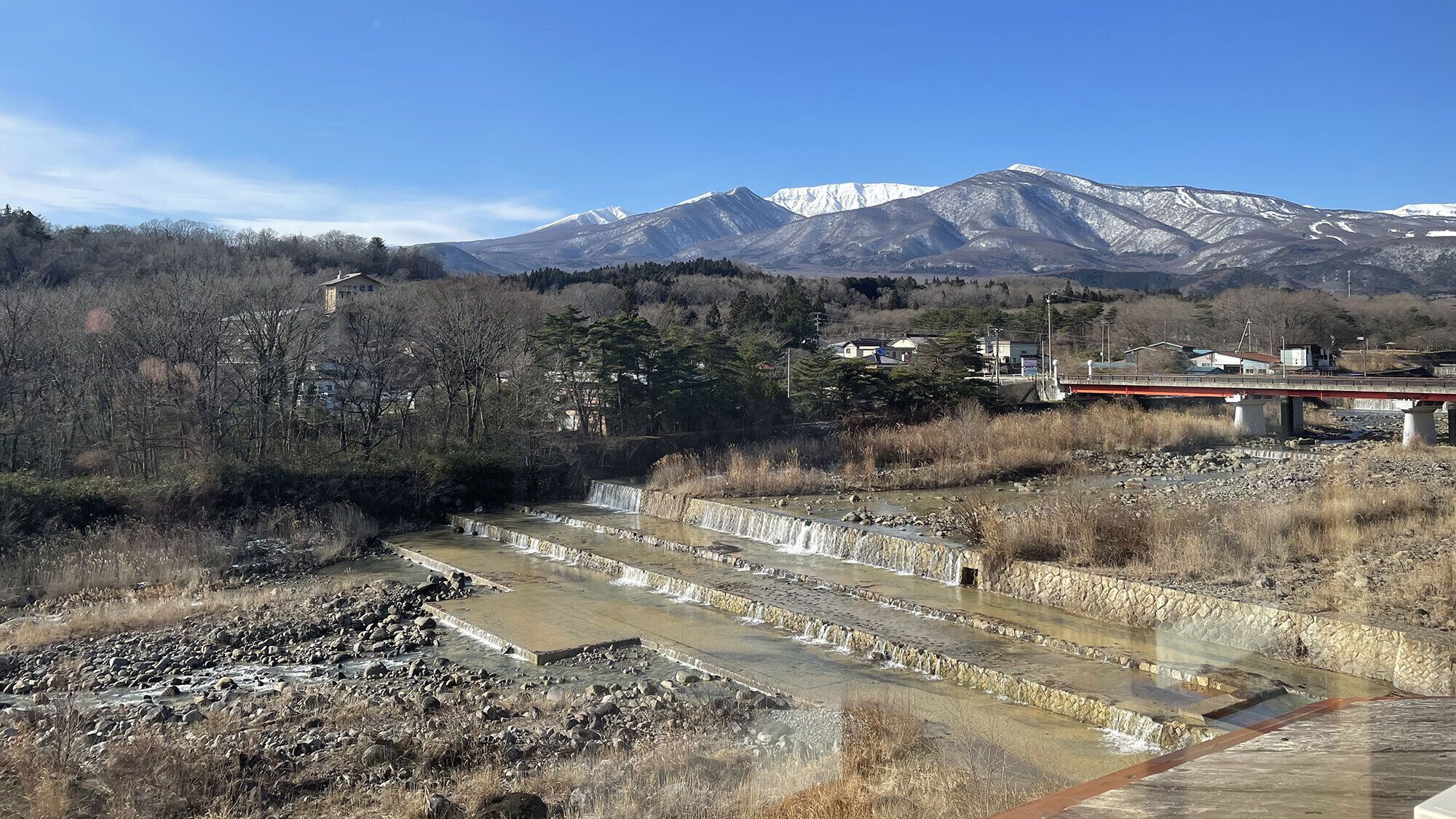 A mountainous landscape with a bridge, a small building, and a series of water channels.