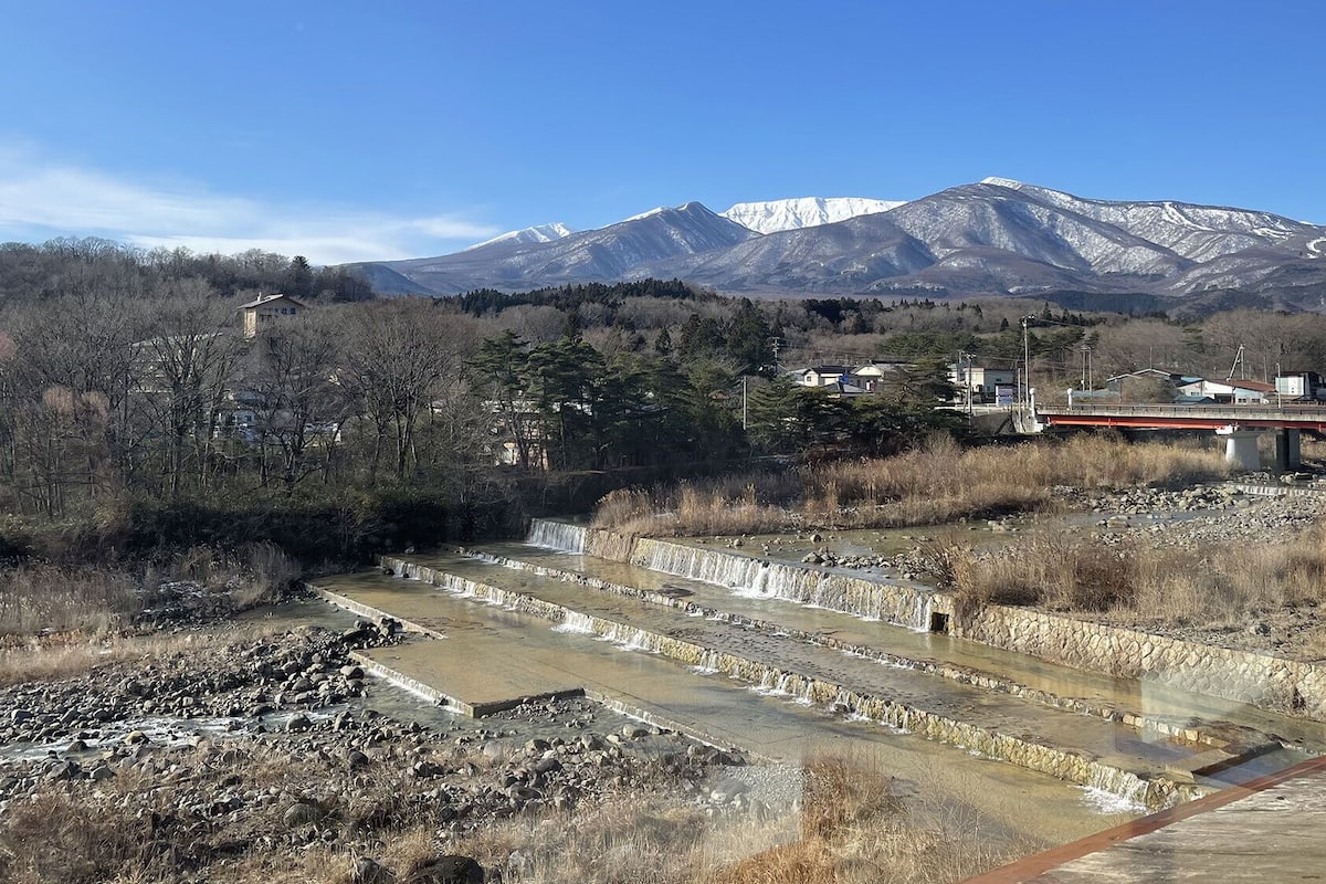 A mountainous landscape with a bridge, a small building, and a series of water channels.