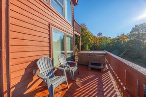 Une terrasse en bois avec deux fauteuils Adirondack et un jacuzzi.