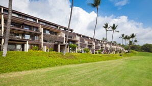 A multi-story hotel with balconies, a well-maintained lawn, and palm trees. - 🏖️Keauhou Golf & Ocean View Condo w/ AC | Bridge-Level Entry (Kailua Kona)