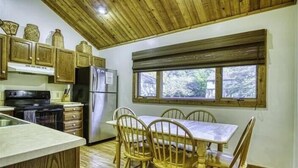 Eine Küche mit Holzausstattung, einem Herd, einem Kühlschrank und einem Esstisch mit Stühlen.