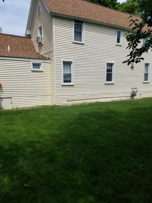 A two-story house with a sloped roof and a well-maintained lawn. - Quirky Cottage Downtown Grand Haven (Grand Haven)