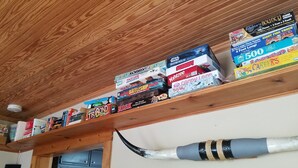 Ein Holzregal mit verschiedenen Gesellschaftsspielen und Puzzles.