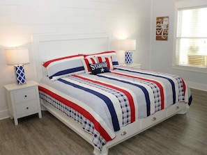A bed with a striped bedspread, two bedside tables with lamps, and a window with blinds.