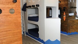 A bunk bed room with a wooden wall, circular cutouts, and a blue wave design at the bottom. - Amazing Grace: 7  BR, 5  BA House in Port Bolivar, Sleeps 25 (Port Bolivar)