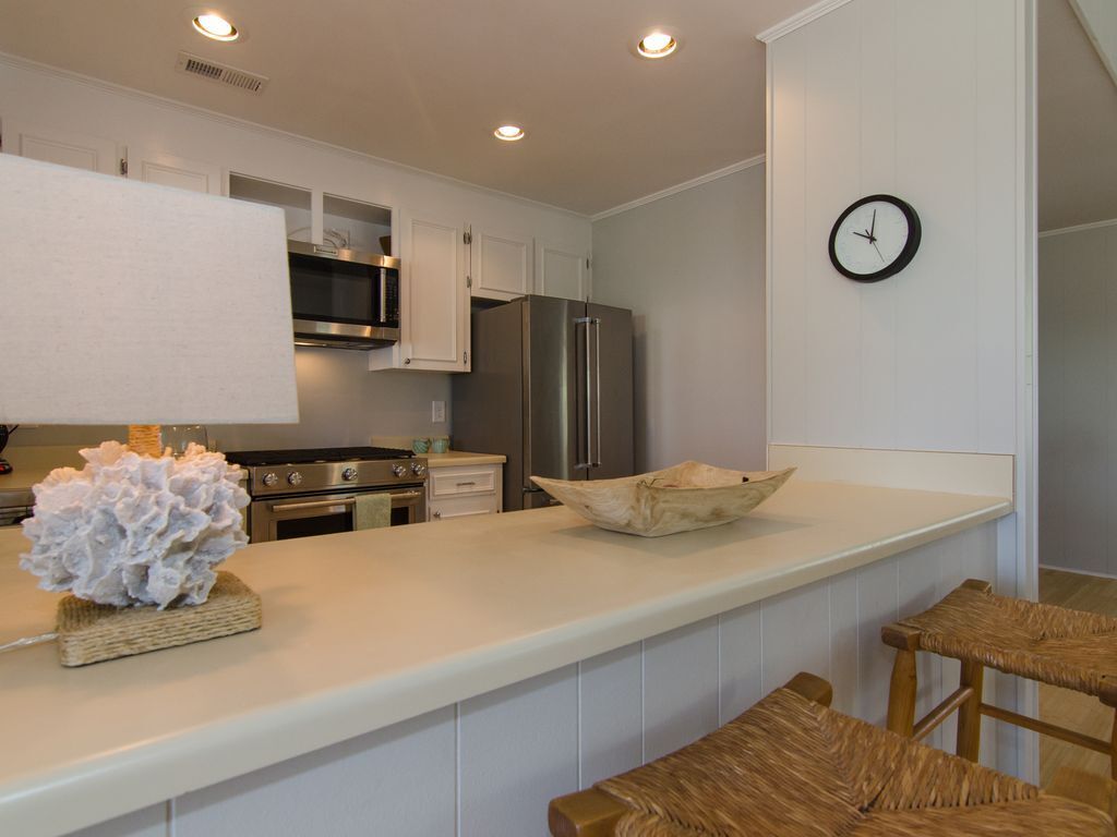 A modern kitchen with white cabinetry, stainless steel appliances, a central island, and a clock on the wall.