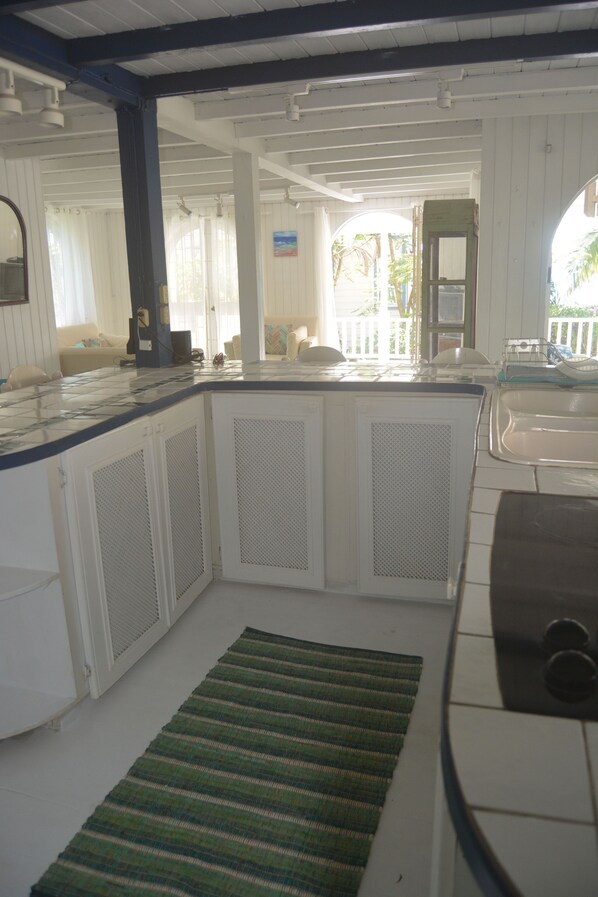A kitchen with white cabinets, a green striped rug, and a view of the outdoor area.