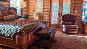 A log cabin bedroom with a large bed, a chair, a desk, and a ceiling fan. - True Ski-in Ski-Out. (Brian Head)