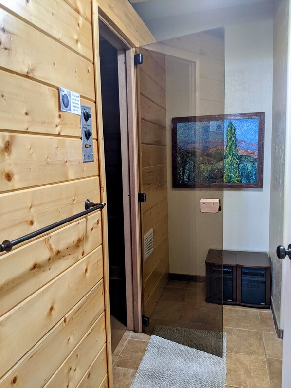 A wooden interior hallway with a door leading to a room, a mounted television, and a small cabinet.