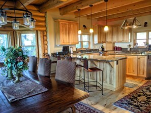 Une cuisine spacieuse dotée de meubles en bois, d’un grand îlot central et d’un coin repas avec une table et des chaises en bois.