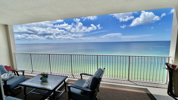 A balcony with a view of the ocean, a table, two chairs, and a potted plant. - Ocean Reef Beach-Front, Luxury, Condo with Awesome Balcony, Highly Rated! (Panama City Beach)