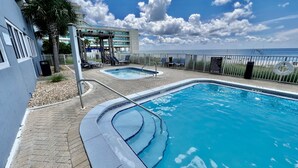 A pool area with two separate pools, a covered seating area, and a view of the ocean. - Ocean Reef Beach-Front, Luxury, Condo with Awesome Balcony, Highly Rated! (Panama City Beach)