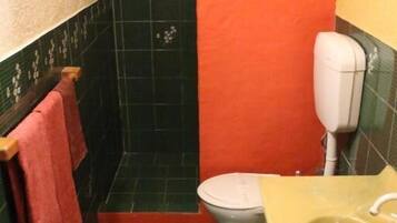A bathroom with a toilet, sink, and shower area.
