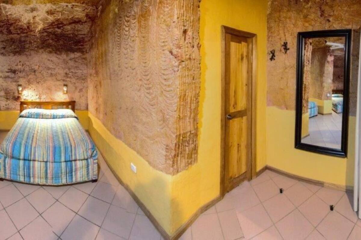 Una habitación con dos camas, una puerta de madera y un espejo que refleja un baño.