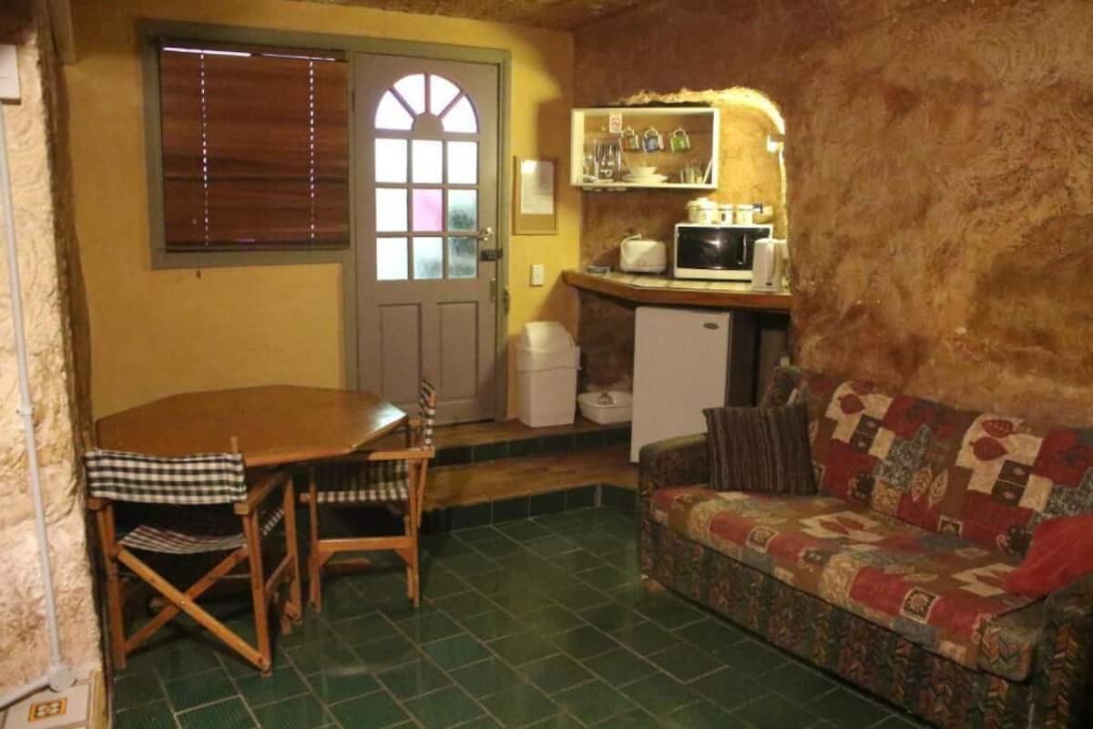 Cocina compacta con mesa, sillas, microondas y sofá.