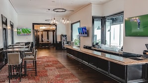 Un hall d’hôtel comprenant un bar, des sièges et un téléviseur diffusant un événement sportif.