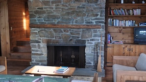 A cozy living room with a stone fireplace, wooden bookshelves, and comfortable seating. - Private beautiful setting, Lyme's best kept secret, Swim, Boat, Fish, Hike (Old Lyme)