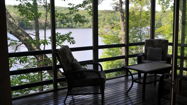 A wooden deck with a view of a lake and trees. There are two chairs and a table. - Private beautiful setting, Lyme's best kept secret, Swim, Boat, Fish, Hike (Old Lyme)