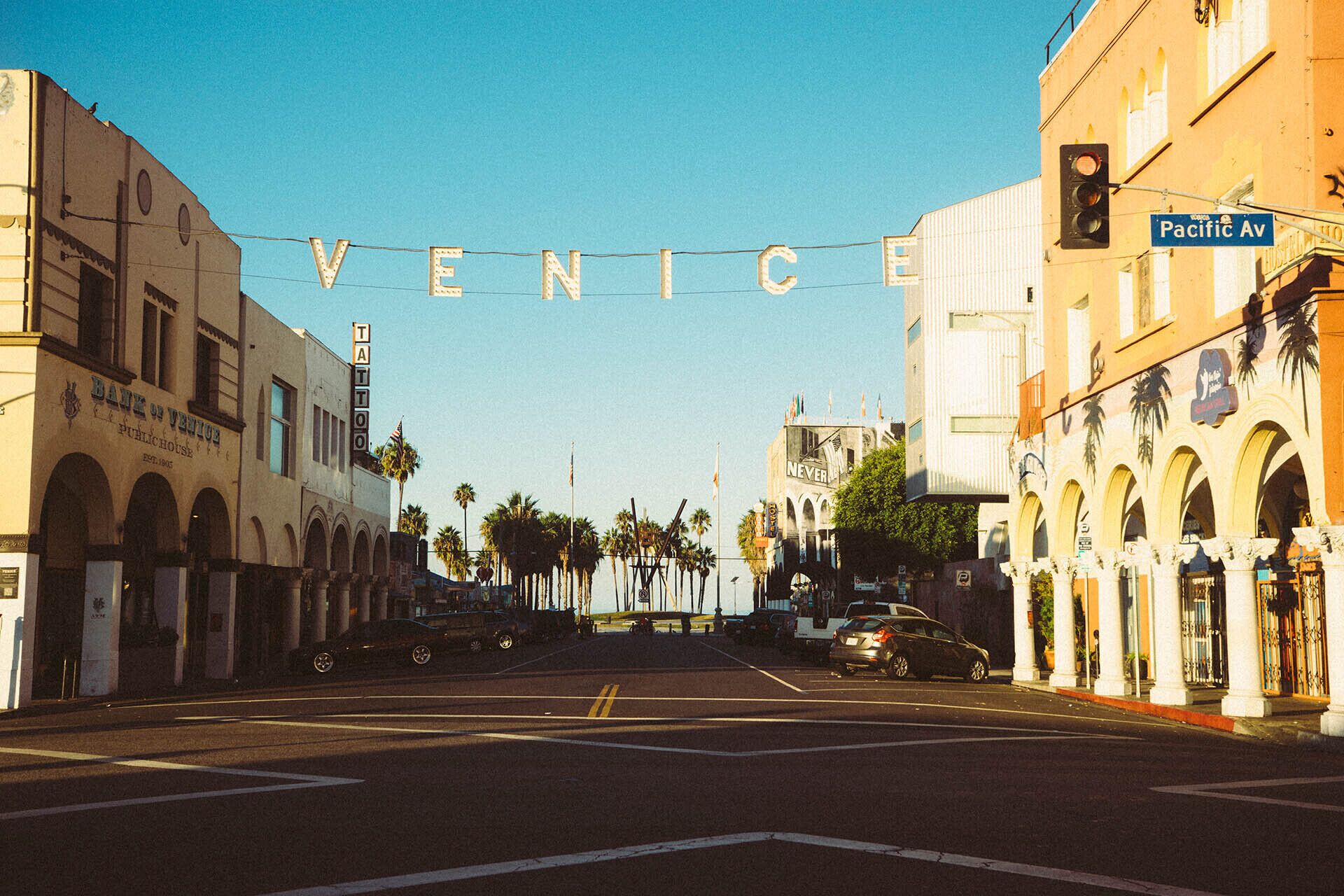 A street view with the word "VENICE" spelled out in lights, buildings with arches, and a traffic light.