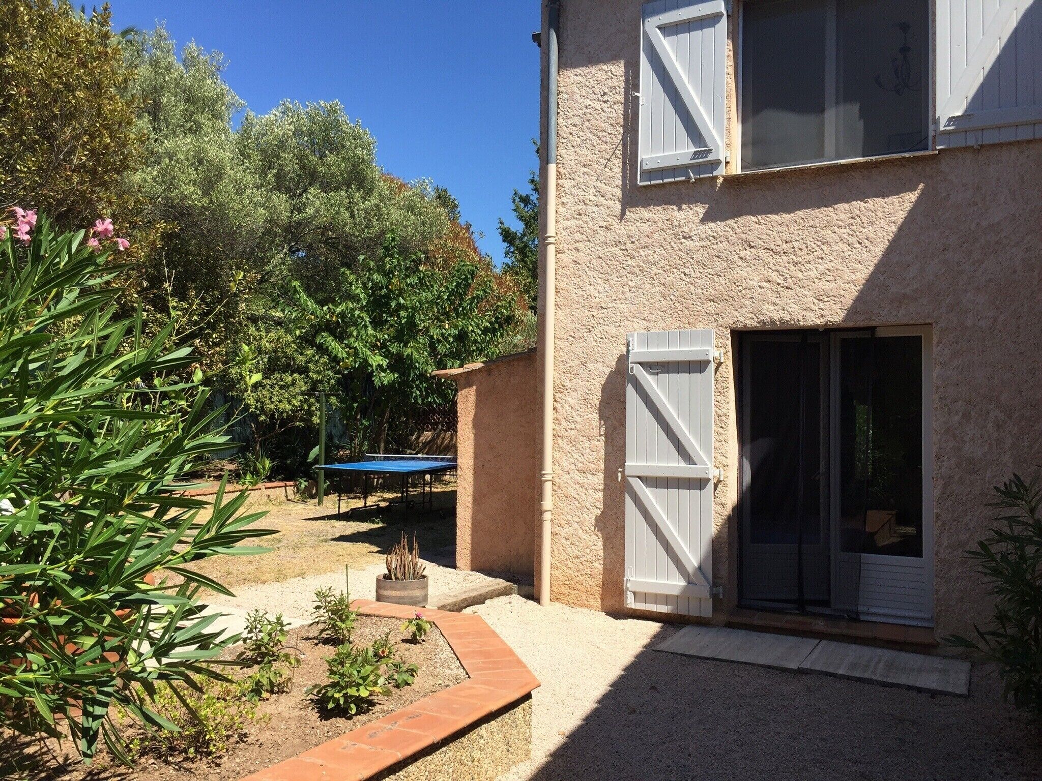 A building with a garden area, a tennis court, and a sliding glass door.
