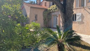 A building with a tiled roof, a door, and a window with a white shutter. - Saint Raphael beautiful villa 170 m2 swimming pool, very quiet, comfortable, residential  (Saint-Raphaël)