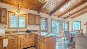 A spacious kitchen with wooden cabinets, a large island, and a dining area with a table and chairs. - HIDDEN VISTA: Distance views from private oversized deck nestled in cool pines. (Munds Park)