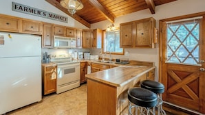 A kitchen with wooden cabinets, a white refrigerator, a stove, and a wooden island with bar stools. - HIDDEN VISTA: Distance views from private oversized deck nestled in cool pines. (Munds Park)