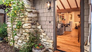Un mur extérieur en pierre avec une porte en bois donnant sur un intérieur doté d’un plancher en bois et d’un espace salon.
