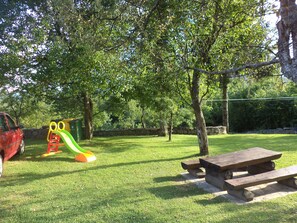 Eine Parkanlage mit Rasenflächen, einem Spielplatz mit Rutsche und Schaukeln sowie einem Picknicktisch.