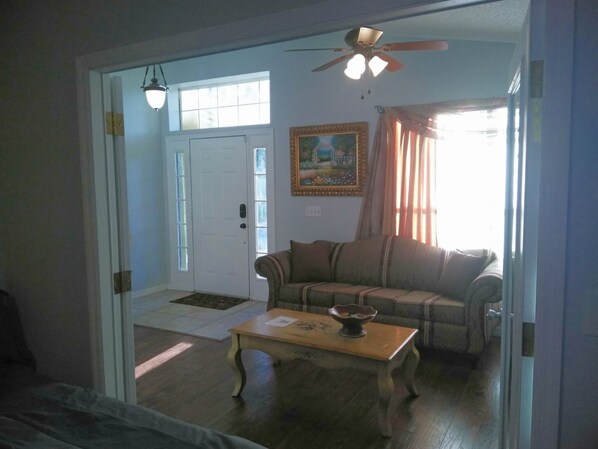 A living room with a sofa, a coffee table, and a ceiling fan. - The Mouse`s neighbor studio near Disney (Clermont)