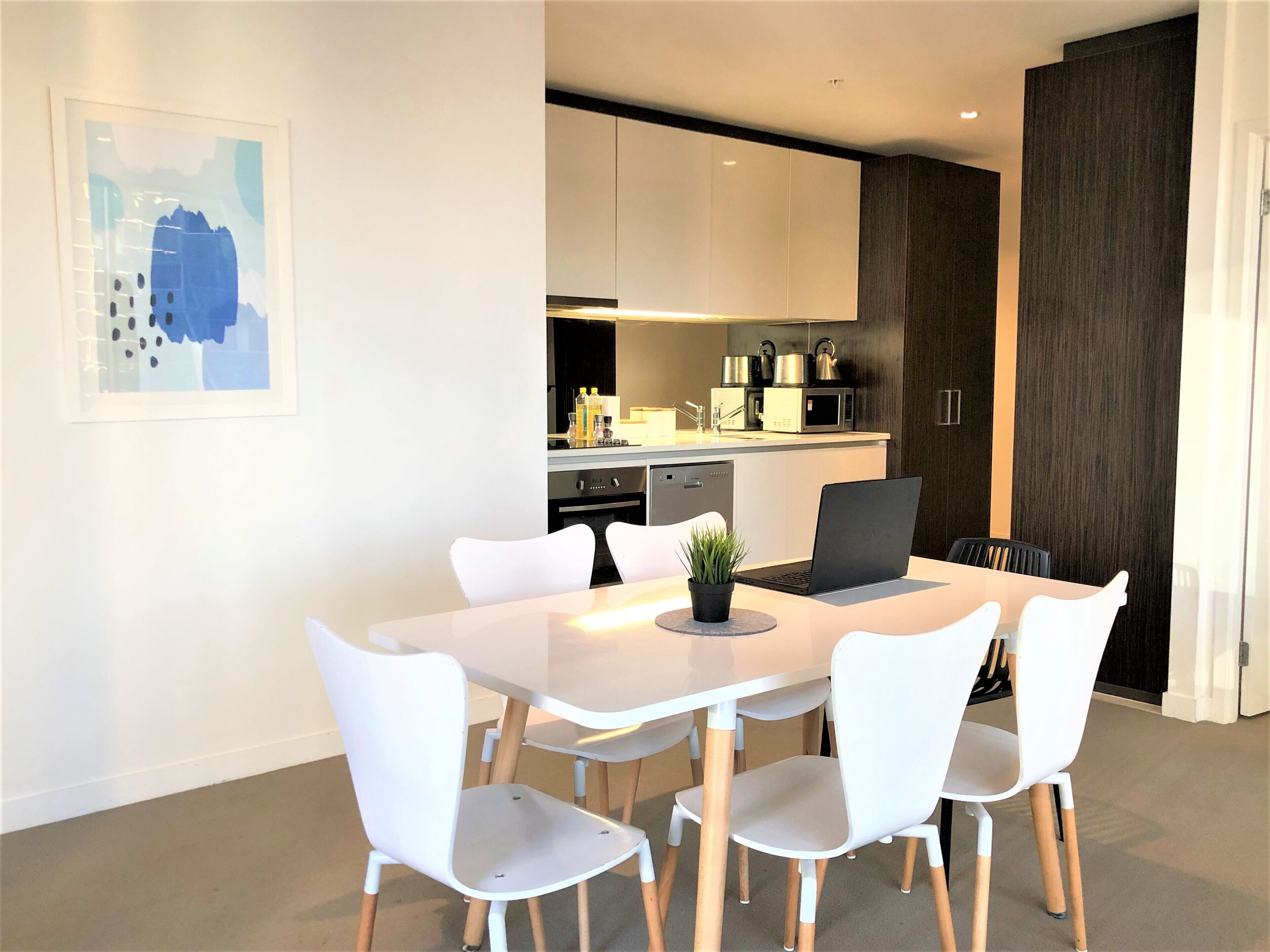 Cocina moderna con armarios blancos, microondas y hervidor.