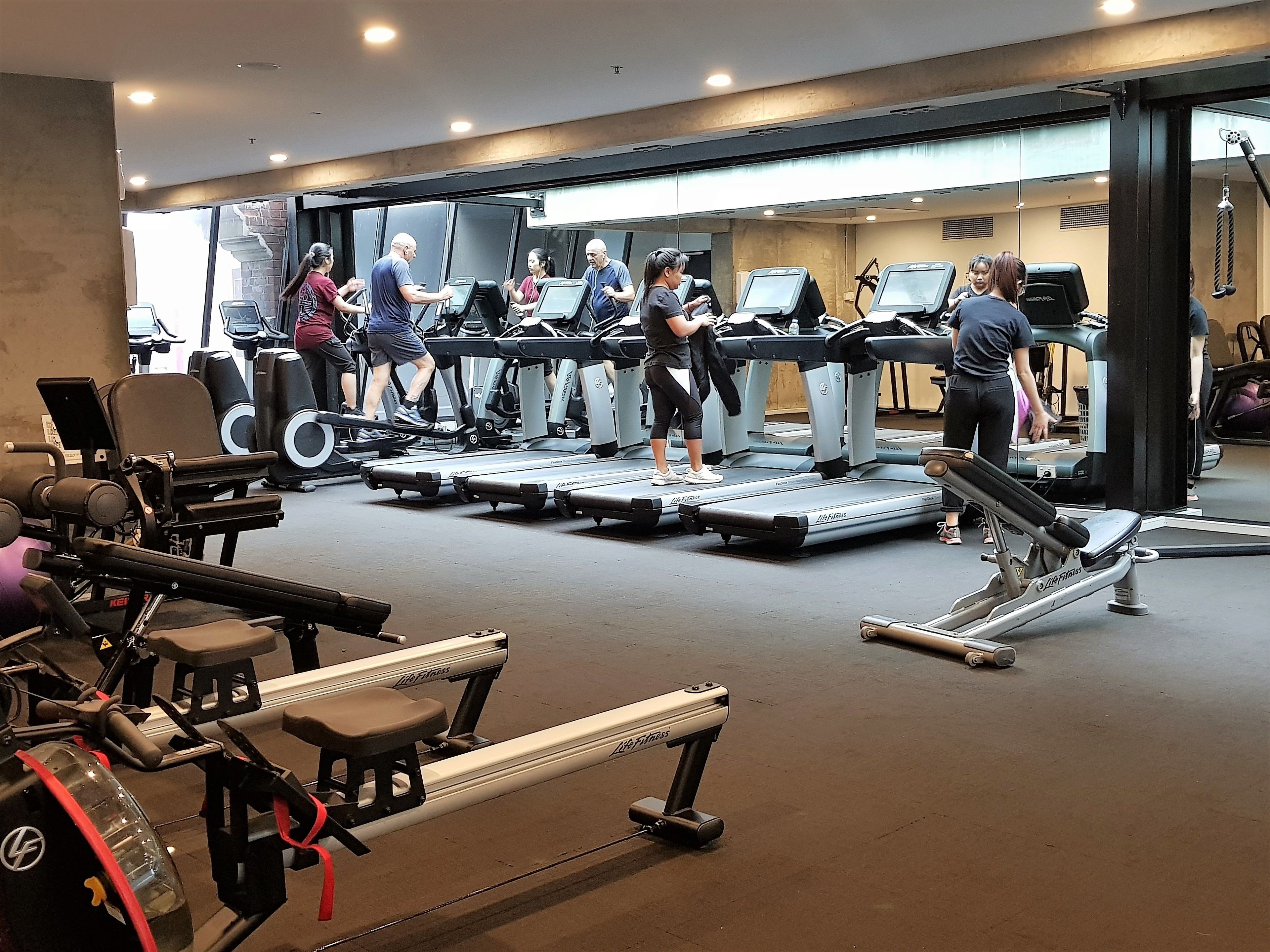 A gym with treadmills, weight machines, and exercise mats.