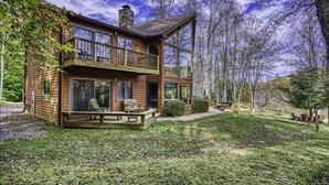 Eine Blockhütte mit Balkon, Veranda und Blick auf den umliegenden Wald.