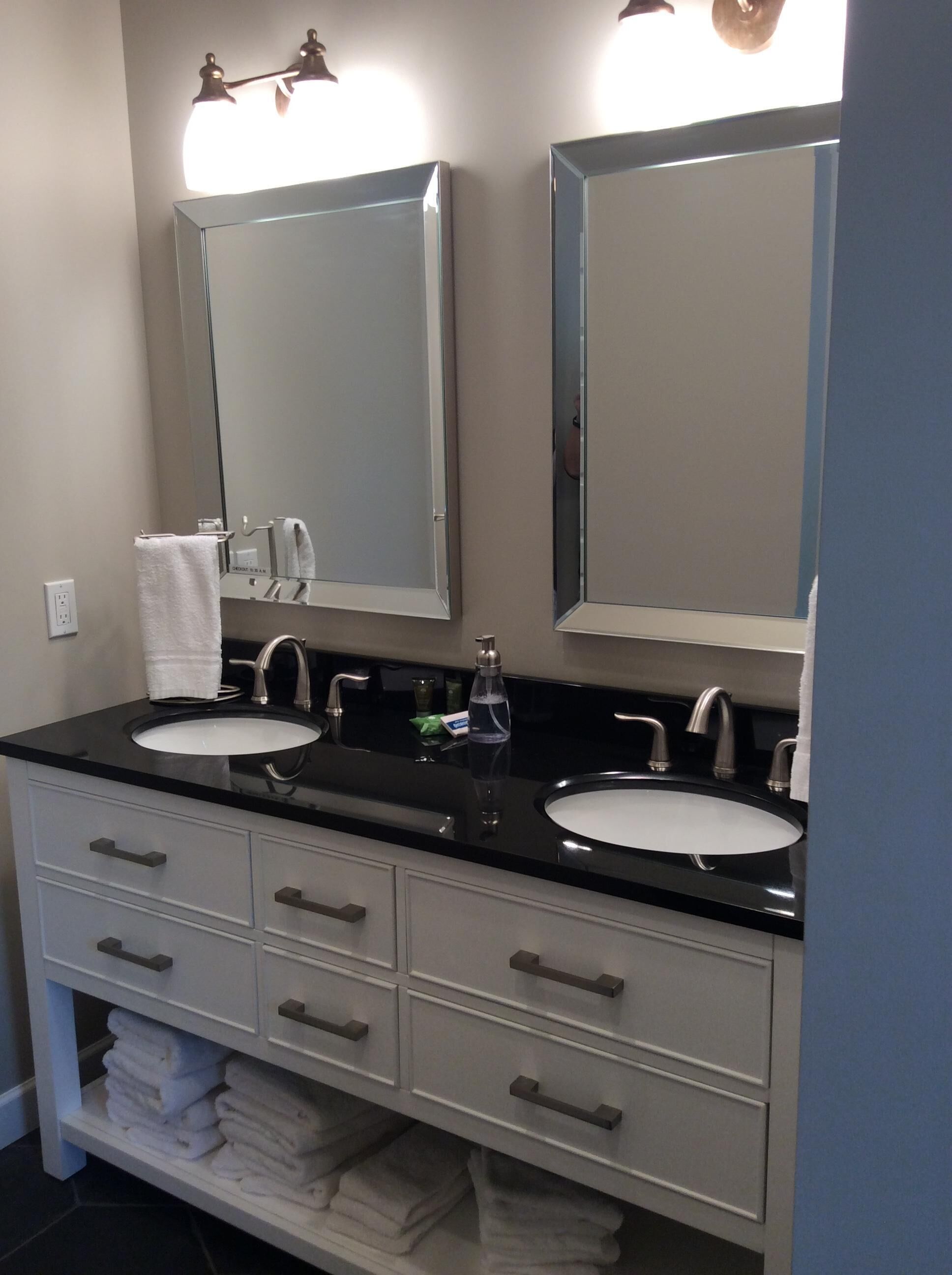 A bathroom with two sinks, a mirror, and a vanity with drawers.