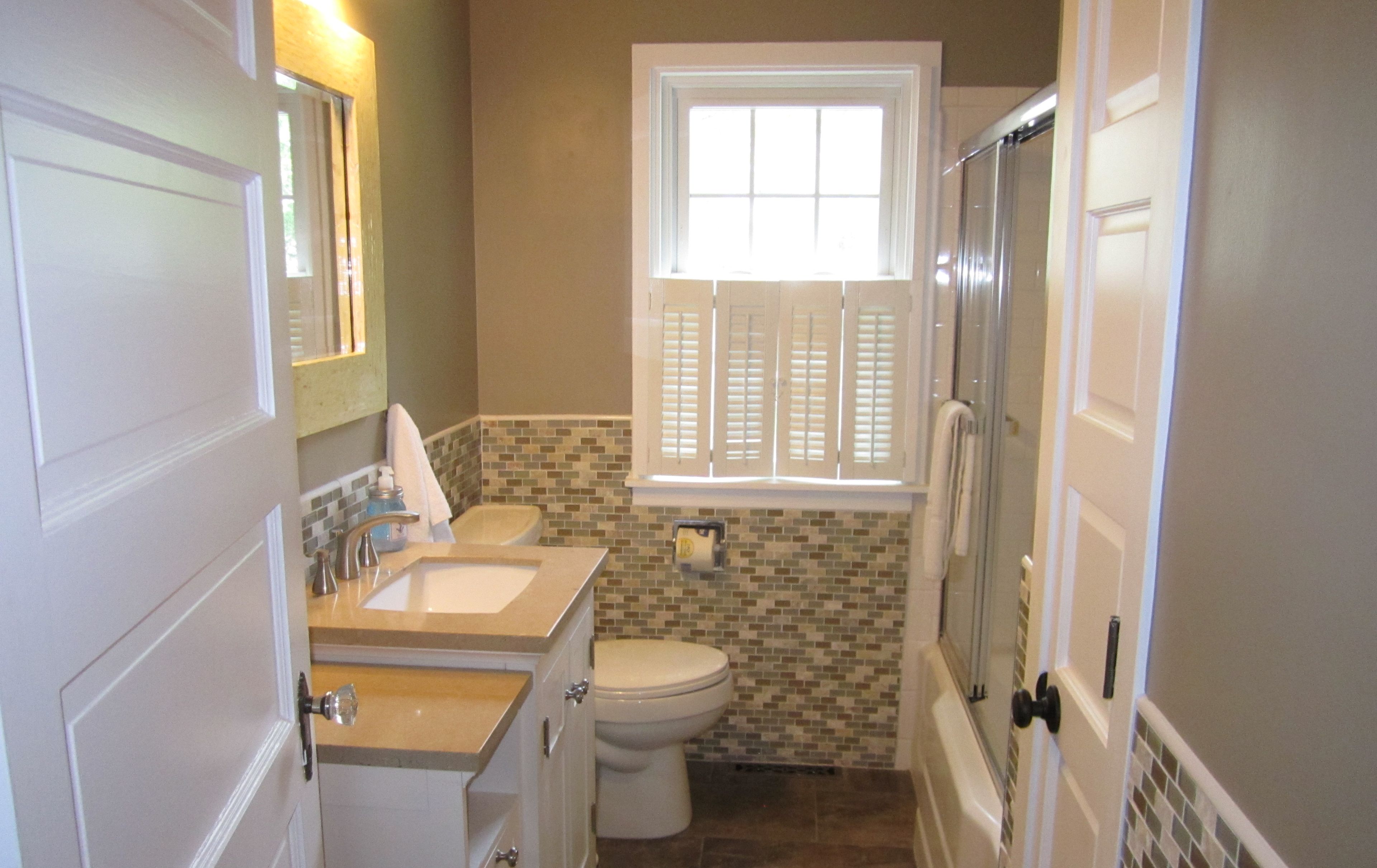 A compact bathroom with a sink, toilet, and shower.