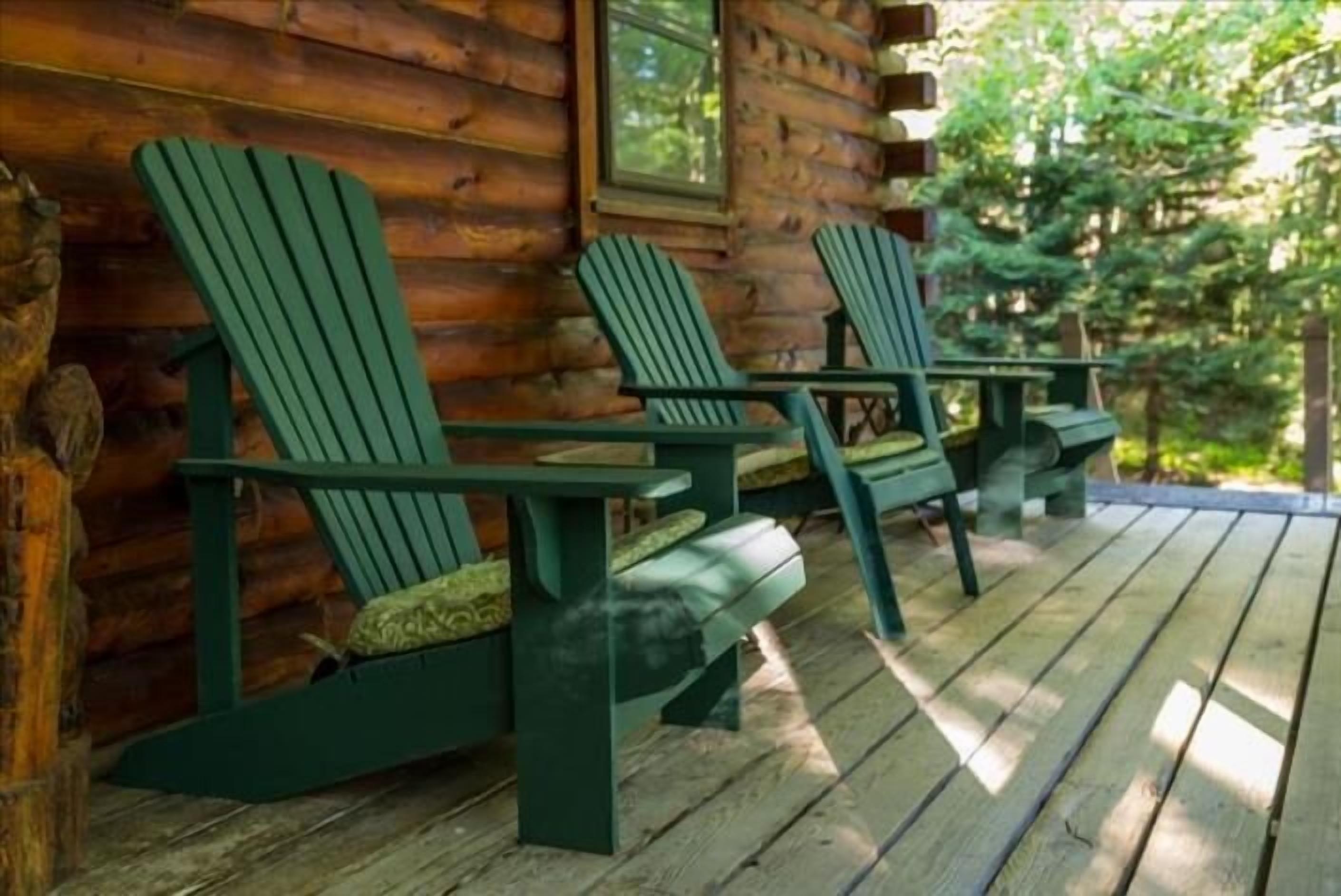 Une cabane en bois dotée d’un porche agrémenté de fauteuils Adirondack.