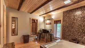 Ein Badezimmer mit einer großen Badewanne, Holzboden, einem Spiegel und einem Fenster mit Jalousien.