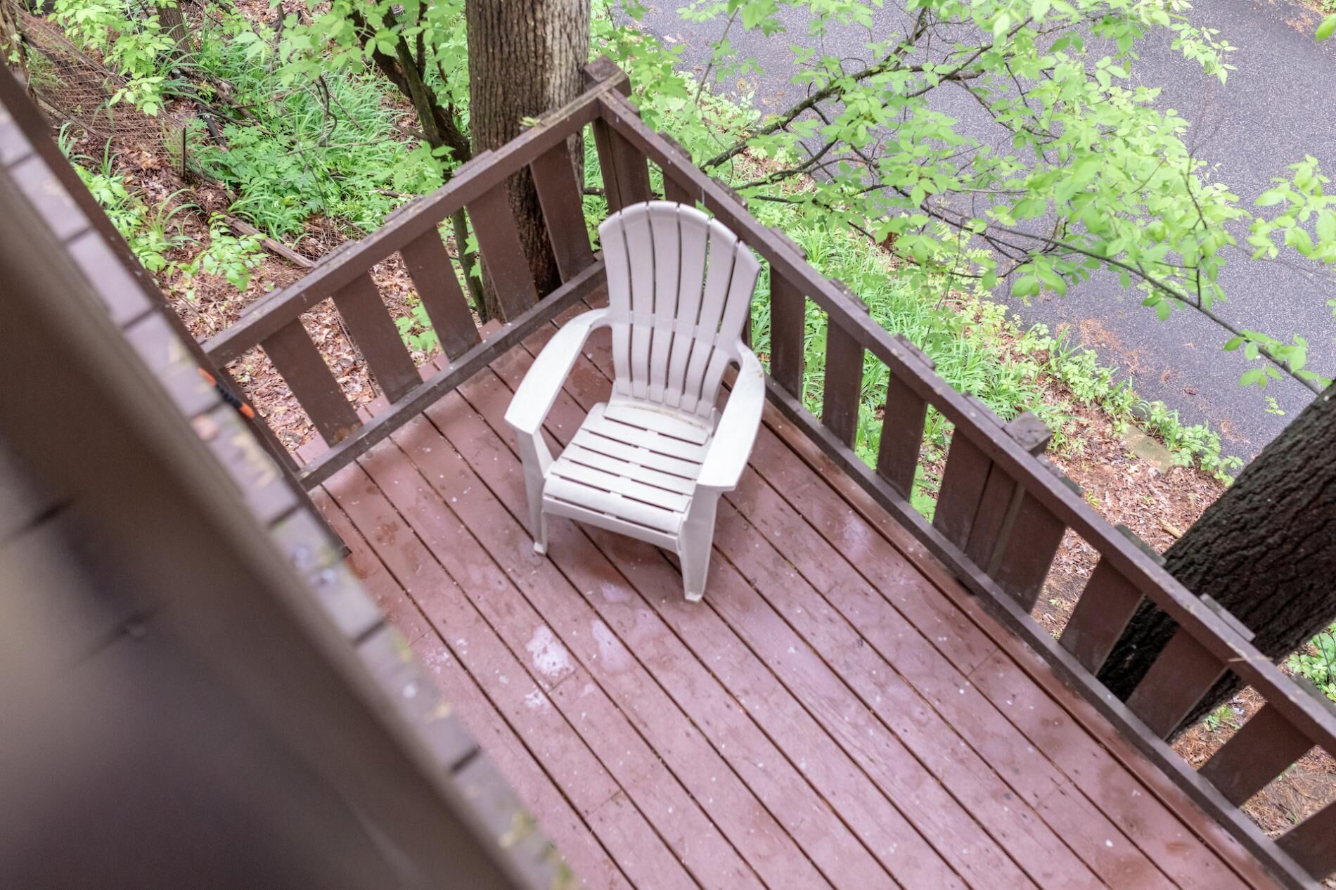 A wooden deck with a white Adirondack chair.