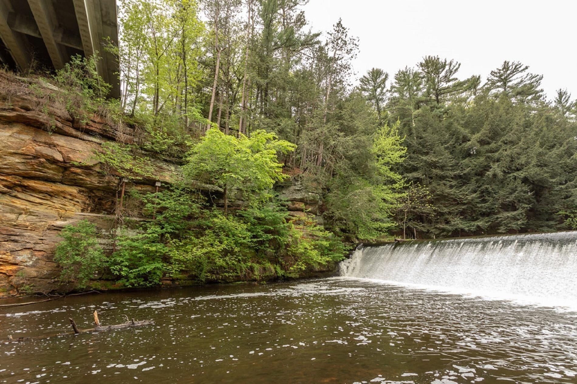 A waterfall cascading over a rocky cliff into a forested area.