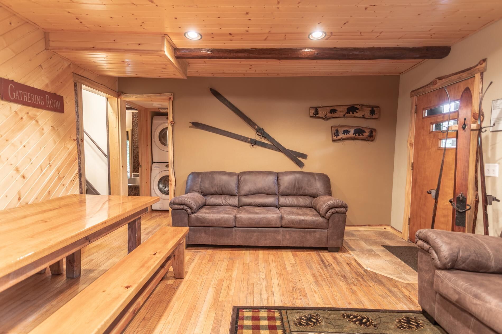 A cozy room with a wooden bench, a leather sofa, and a washing machine in the background.