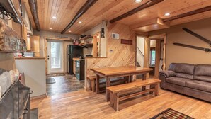 Ein gemütliches Blockhaus-Interieur mit einem Holztisch, einer Couch und einer Küchenzeile.