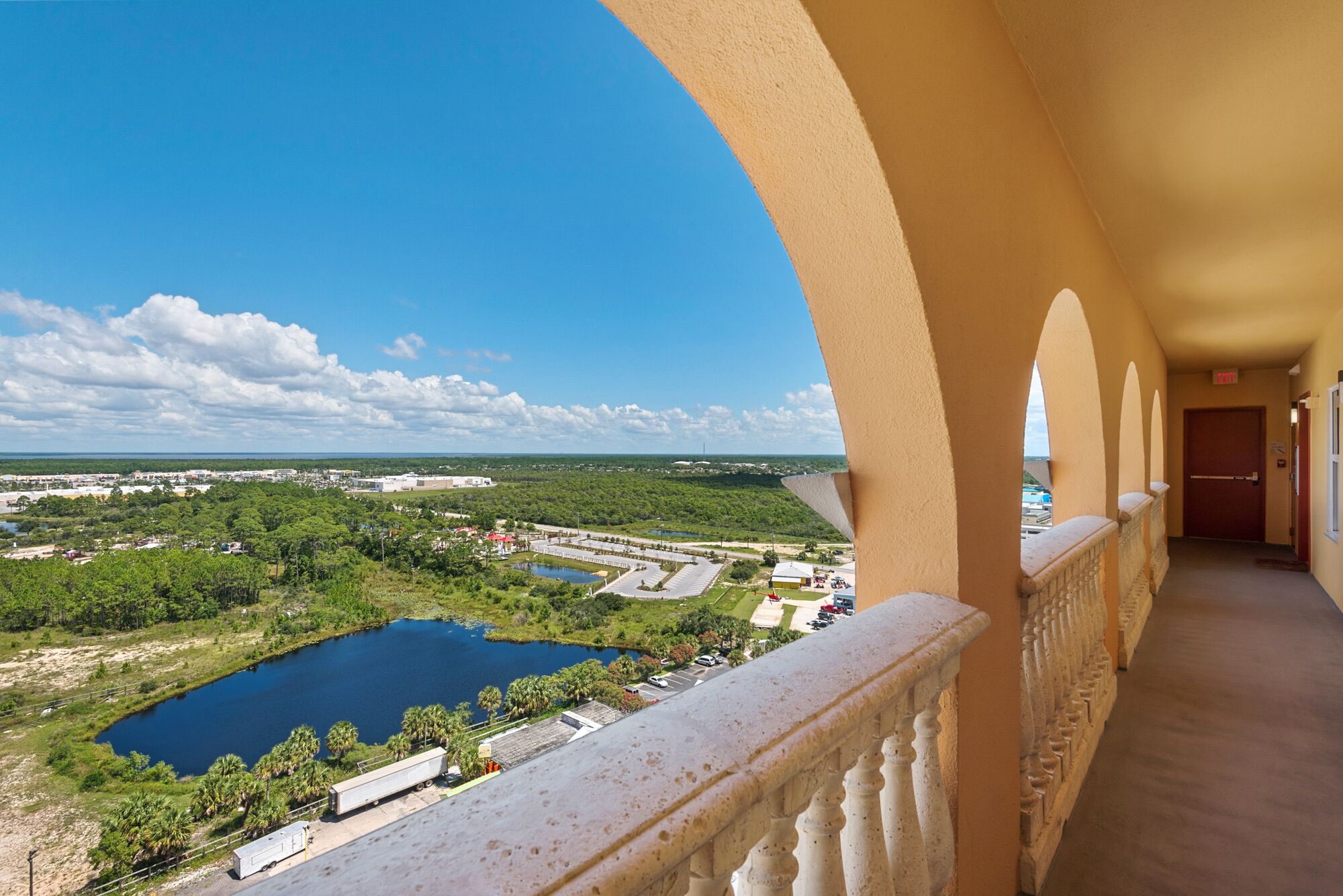 A balcony with a view of a lake, buildings, and greenery.