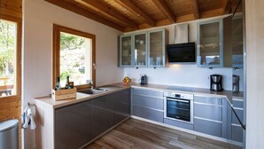 Een moderne keuken met houten balken, een groot raam, roestvrijstalen apparatuur en een inbouwoven.
