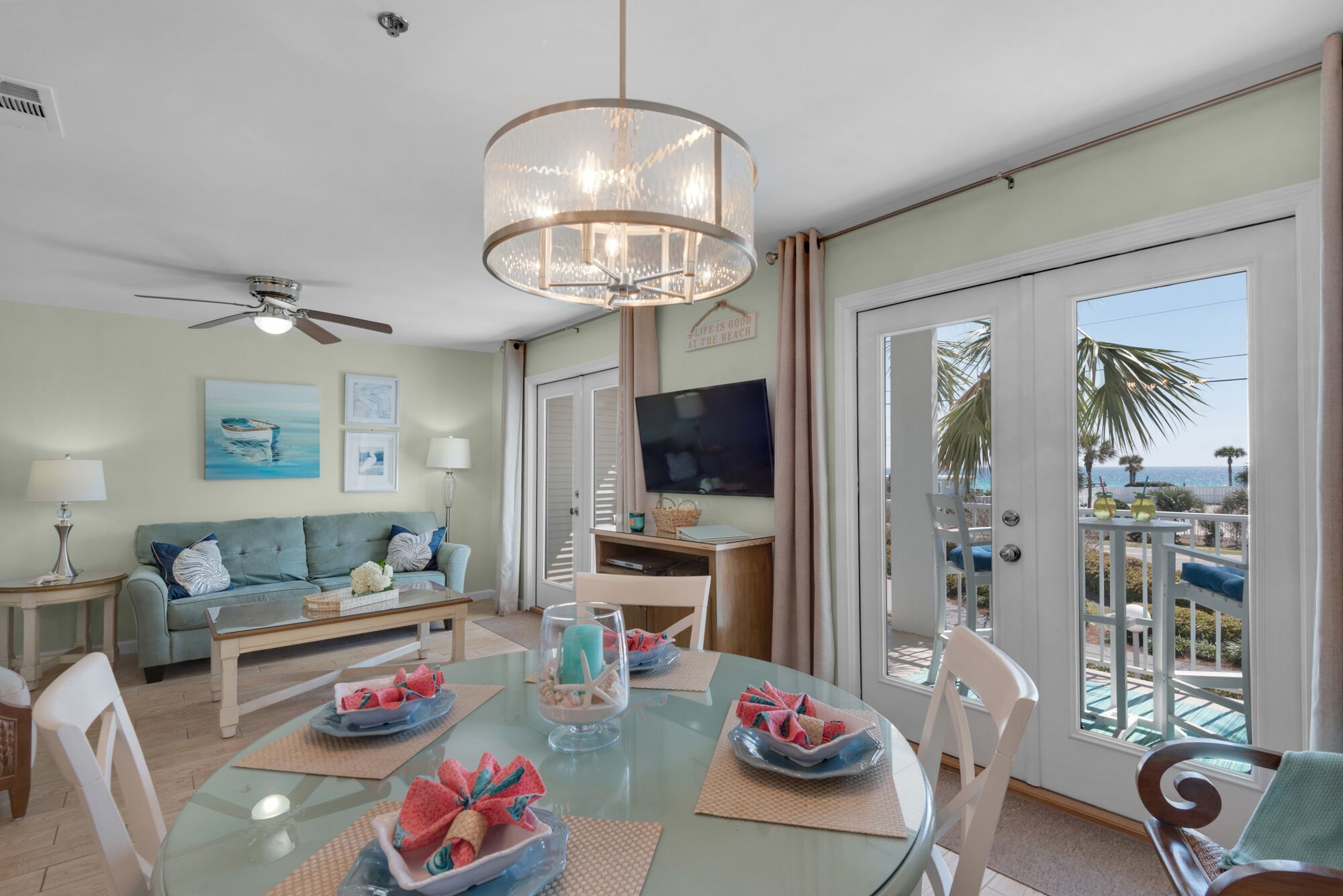 A spacious living room with a glass dining table, a sofa, and a television.