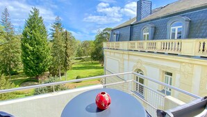Een balkon met een tafel, stoelen en een rode vaas.