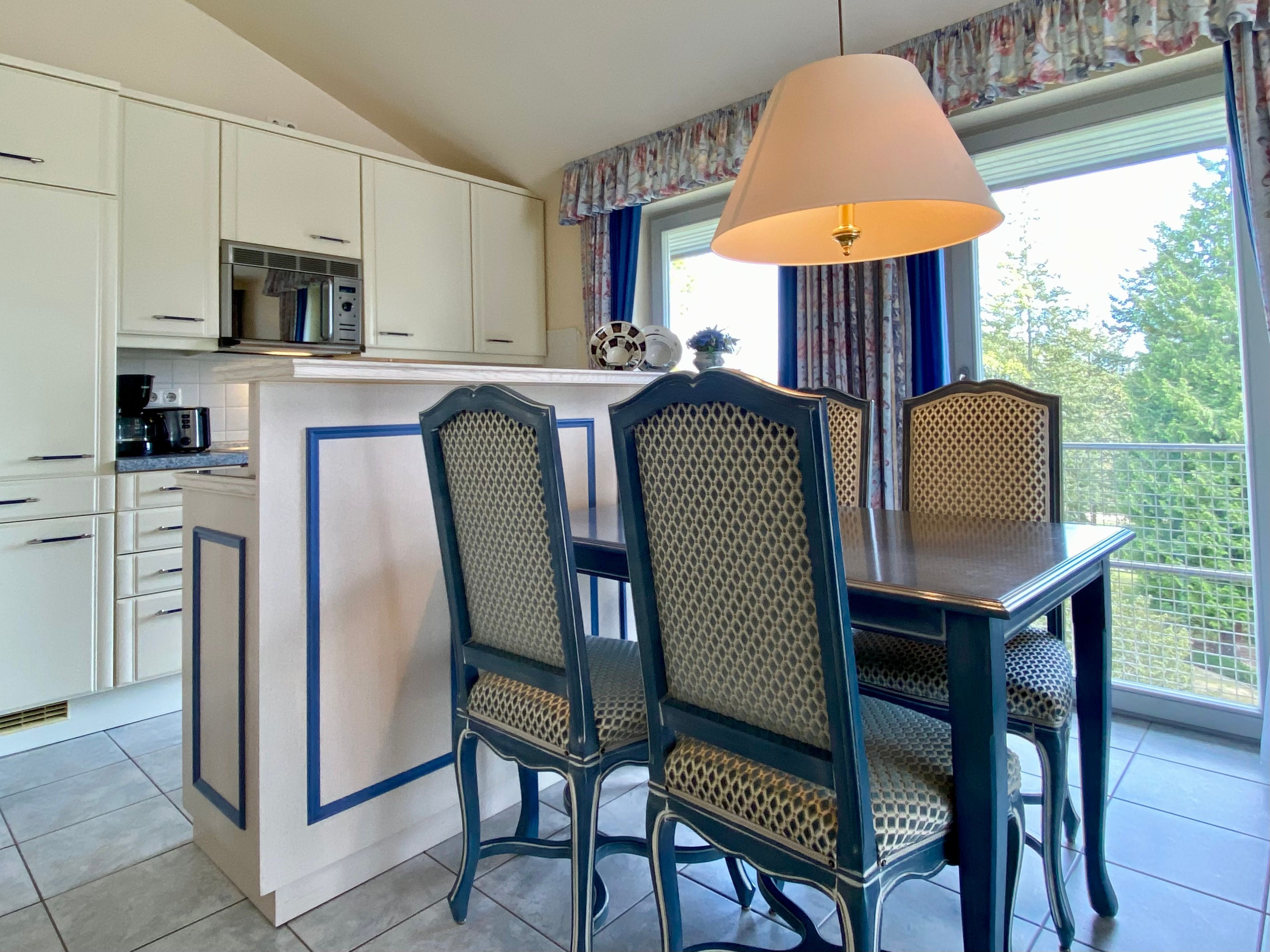 A kitchen with white cabinets, a microwave, and a table with chairs.