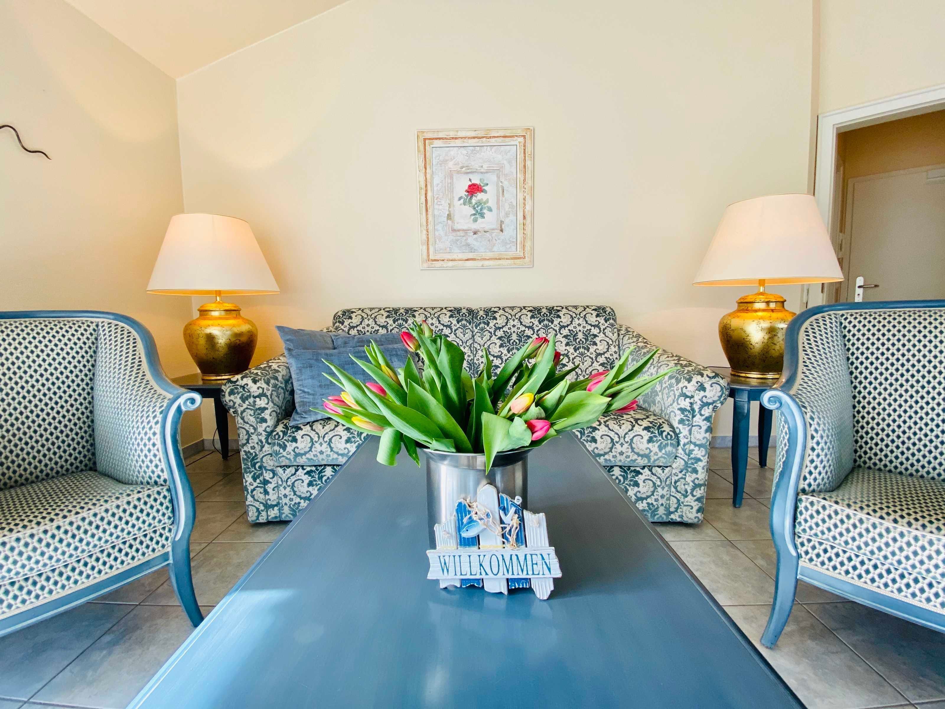 Un salon avec des canapés à motifs, une table basse et deux lampes.